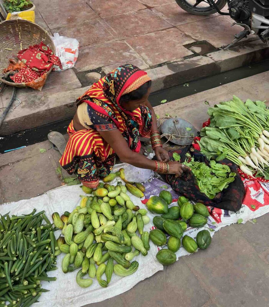 Venditrice di verdura nei mercati locali della città vecchia di Varanasi lungo i ghat del Gange in India